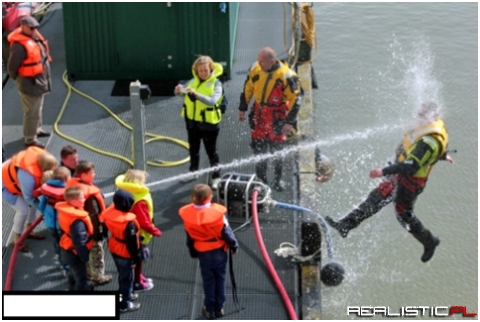Kids playing with a water hose during coast guard demonstration